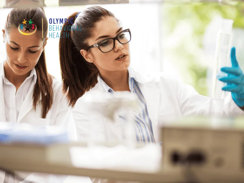 Two female scientists in lab coats examining samples in a laboratory, representing research into hereditary addiction