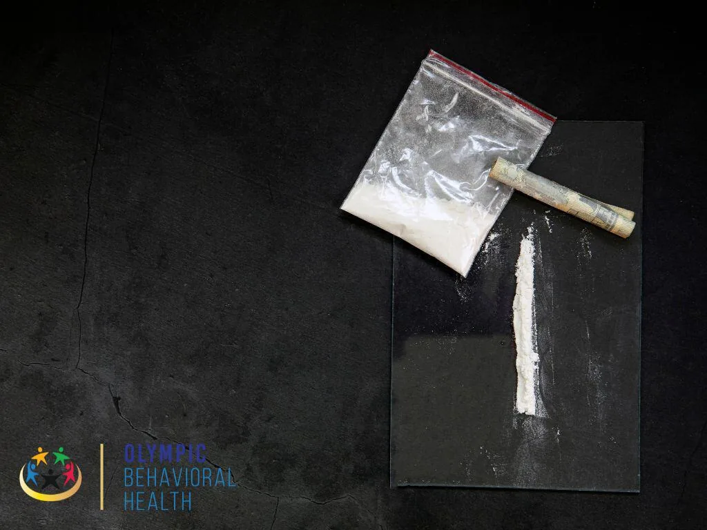 Bag of white powder, a rolled bill and a line of powder on a dark surface, illustrating angel dust (PCP) use