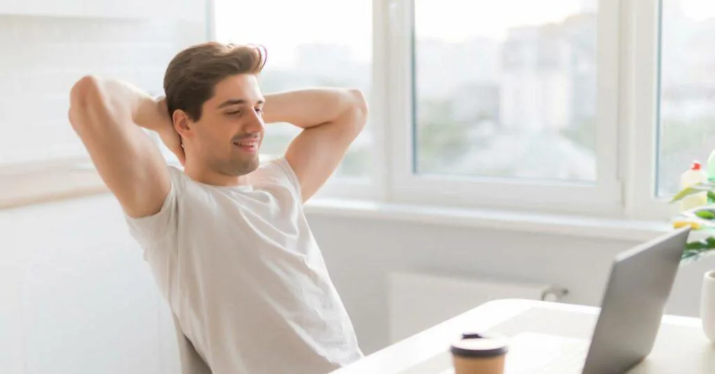 Relaxed man leaning back with hands behind his head at a desk, illustrating calm after anger management counseling