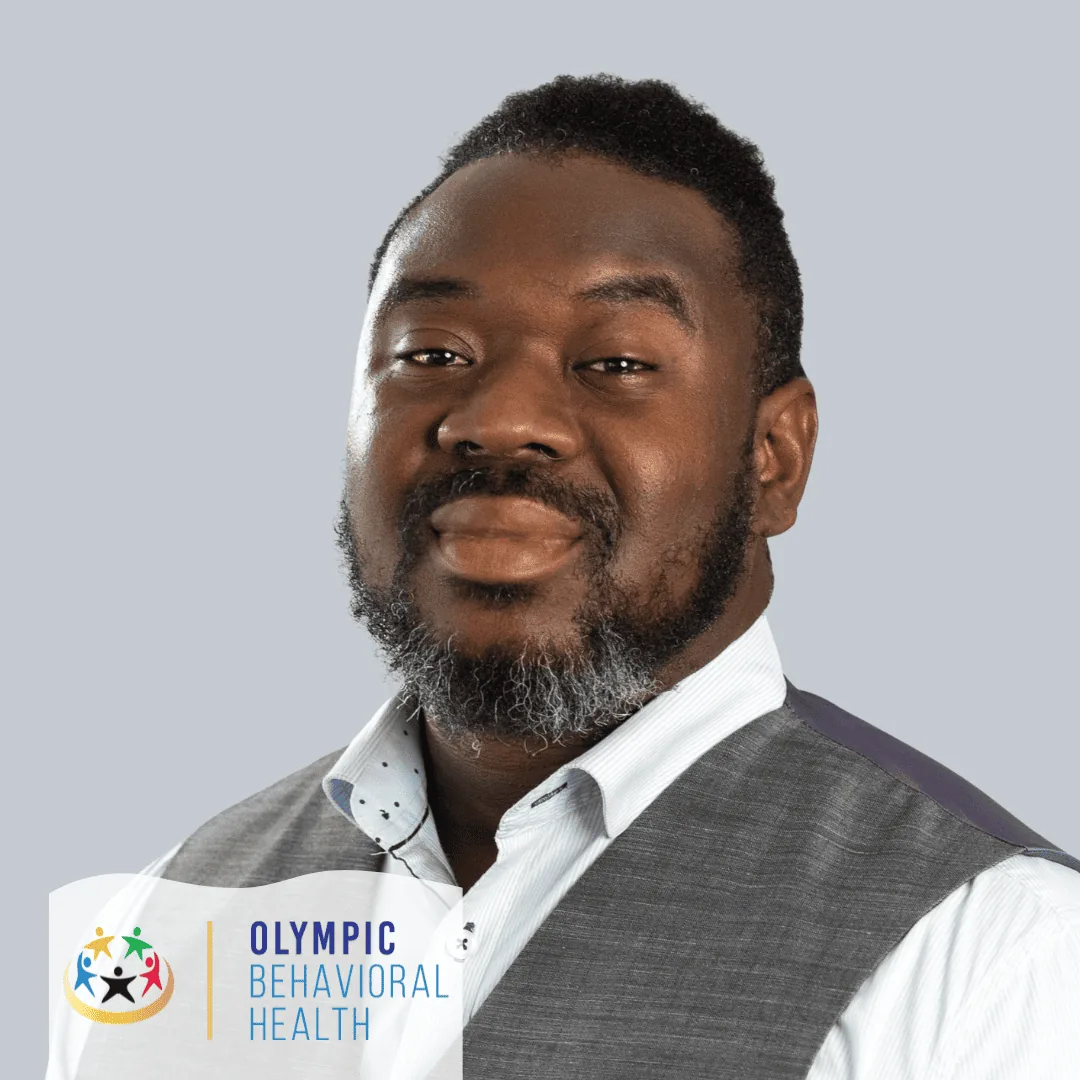Bronson Theodore, Lead Behavioral Health Technician at Olympic Behavioral Health, smiling in a vest and white shirt