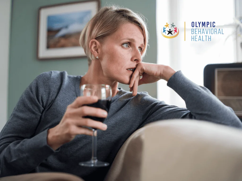 Woman holding a glass of red wine and staring anxiously into the distance, illustrating common mental health disorders