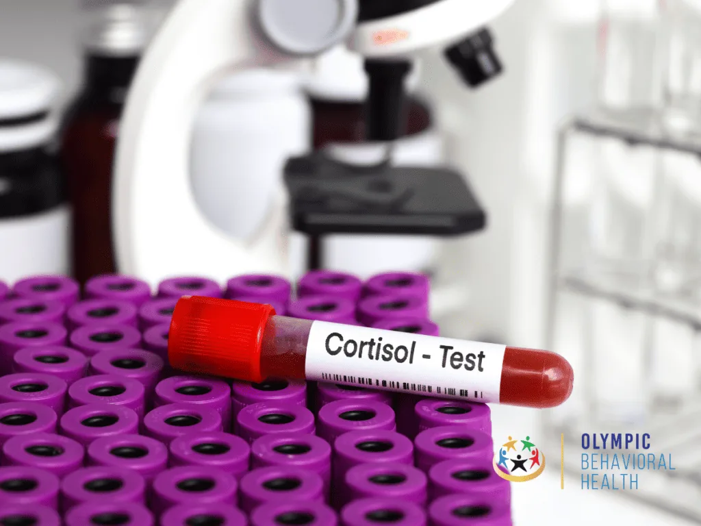 Blood sample tube labeled Cortisol - Test in a rack of purple vials beside a microscope, illustrating cortisol release