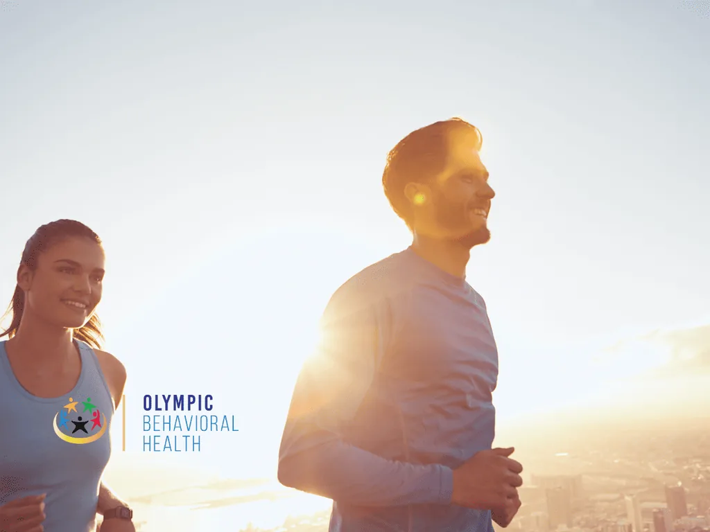 Smiling couple jogging outdoors at sunrise, showing exercise and healthy routines that support well-being in recovery