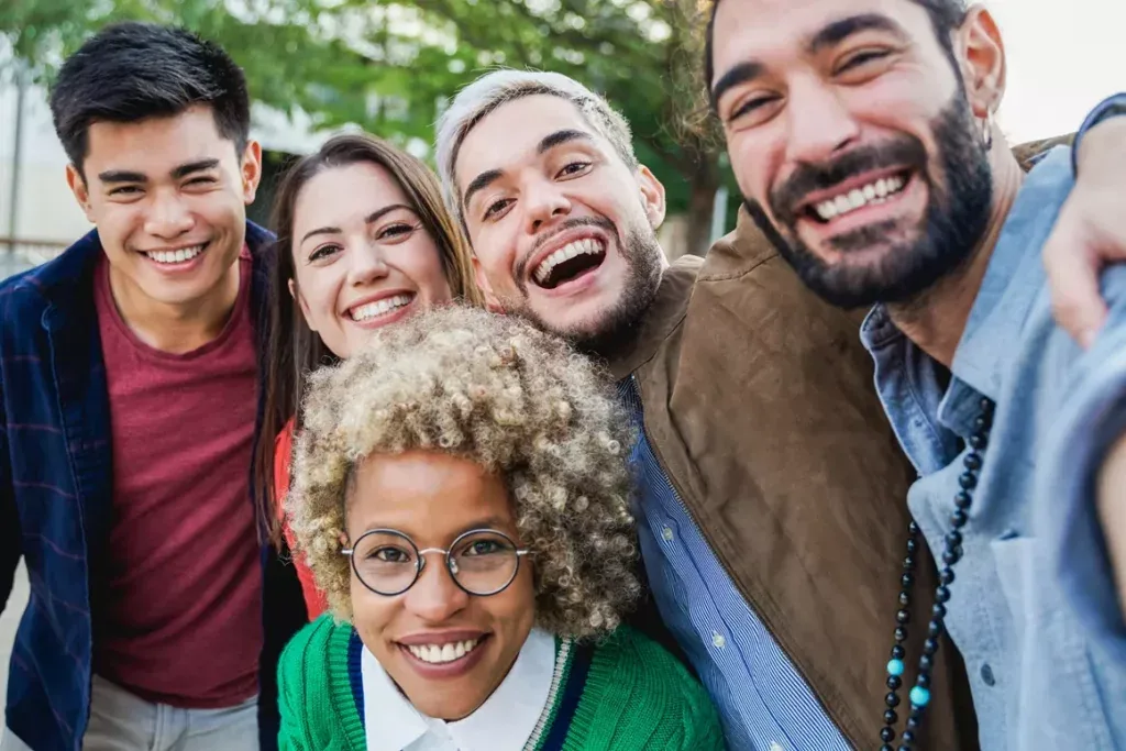 Smiling group of diverse young adult friends taking a selfie, showing connection and support in addiction recovery