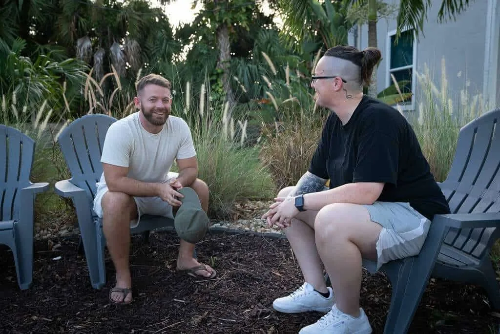 Two men talking in Adirondack chairs in the garden at Olympic Behavioral Health, illustrating motivational interviewing
