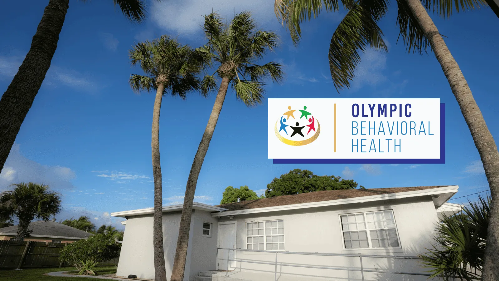 Olympic Behavioral Health building in Lantana framed by tall palm trees under blue sky, with the logo sign