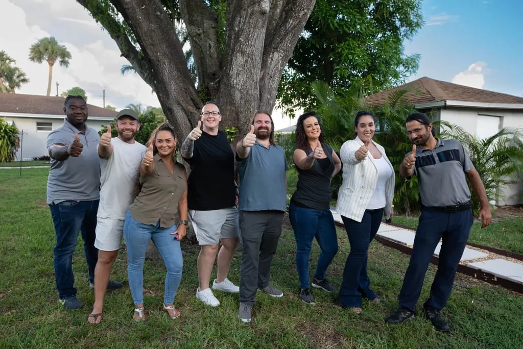 Olympic Behavioral Health team members giving thumbs up under a large tree on the facility lawn