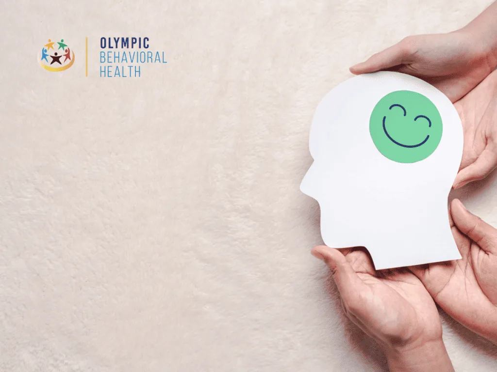 Hands holding a paper head cutout with a smiling face, representing oxytocin's effect on mood and relapse prevention