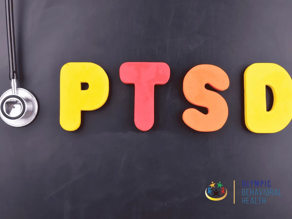 Colorful letters spelling PTSD on a dark chalkboard next to a stethoscope, introducing PTSD signs, symptoms and causes