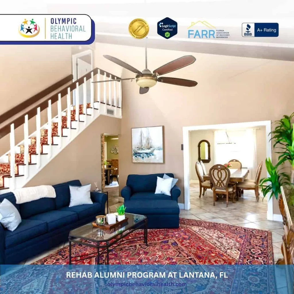 Living room with staircase, navy sofas and red rug, captioned Rehab Alumni Program at Lantana, FL