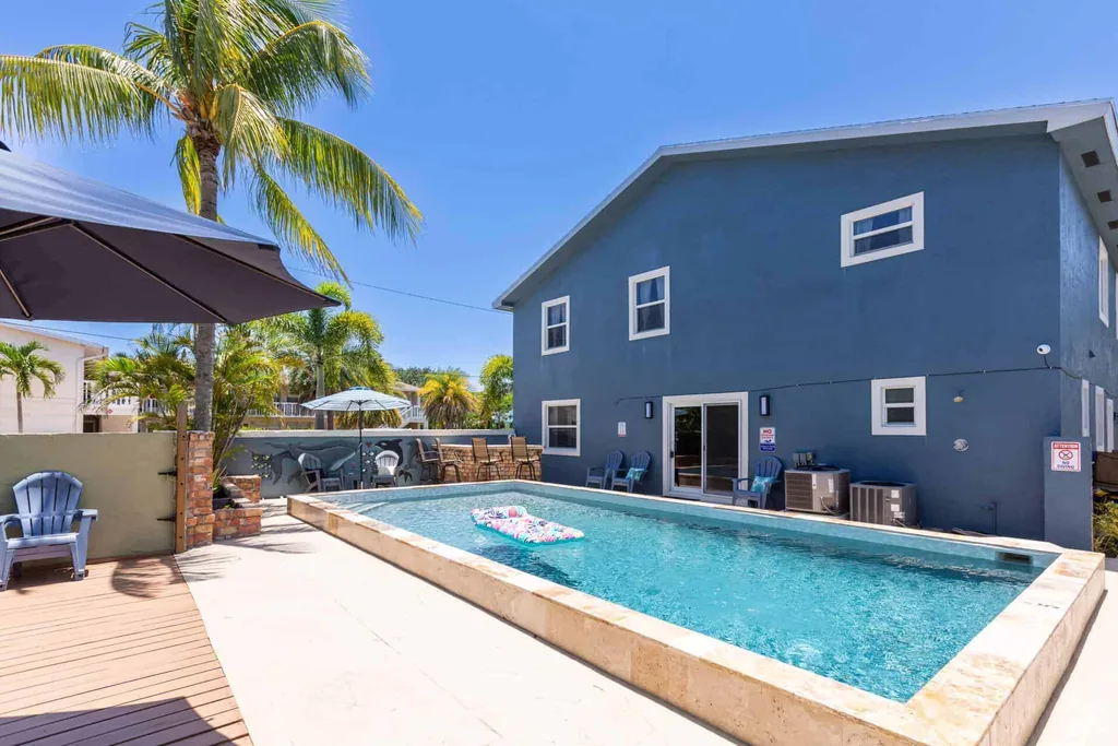 Pool and palm trees beside the blue two-story residence, shown on the insurance verification page for addiction treatment