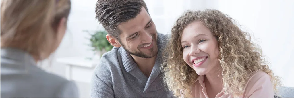 Smiling couple talking with a counselor, illustrating education and resources for trauma and addiction